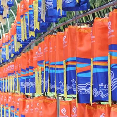 Illuminated character-shaped lanterns floating on the Namgang River at night with reflections doubling the color in the water at the Jinju Lantern Festival